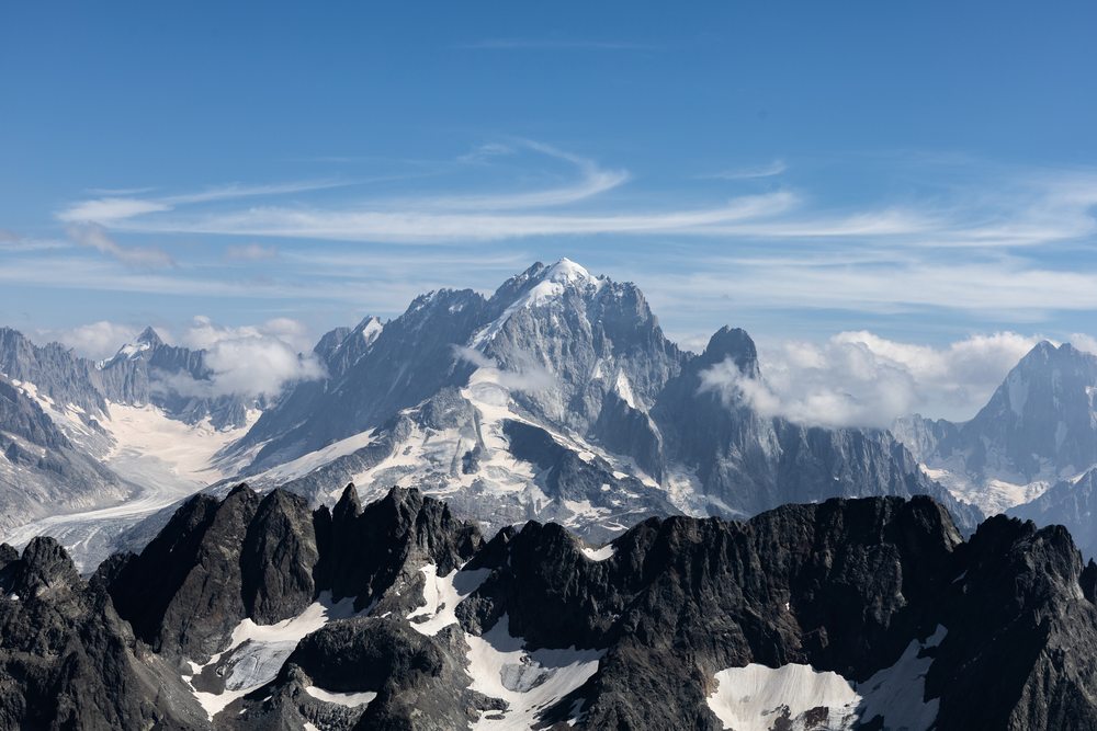 Snow-covered peaks and glaciers beyond a dark rocky ridge.