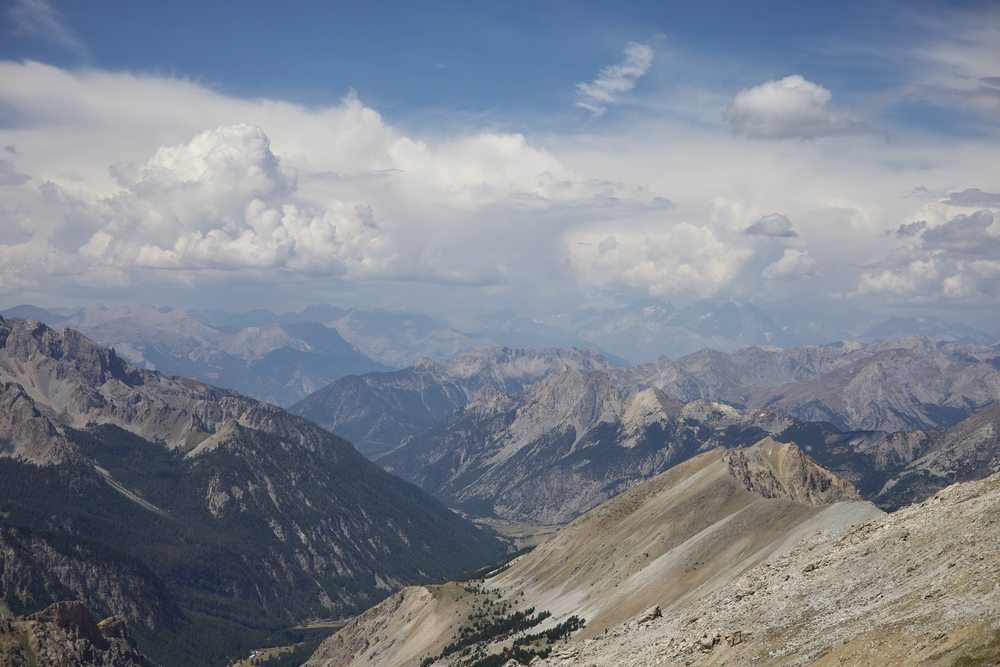 Successive rocky mountain ridges beneath a bank of clouds.