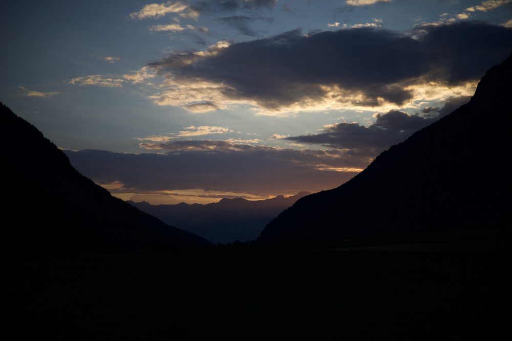 A sunset sky framed by the dark silhouettes of two mountains.