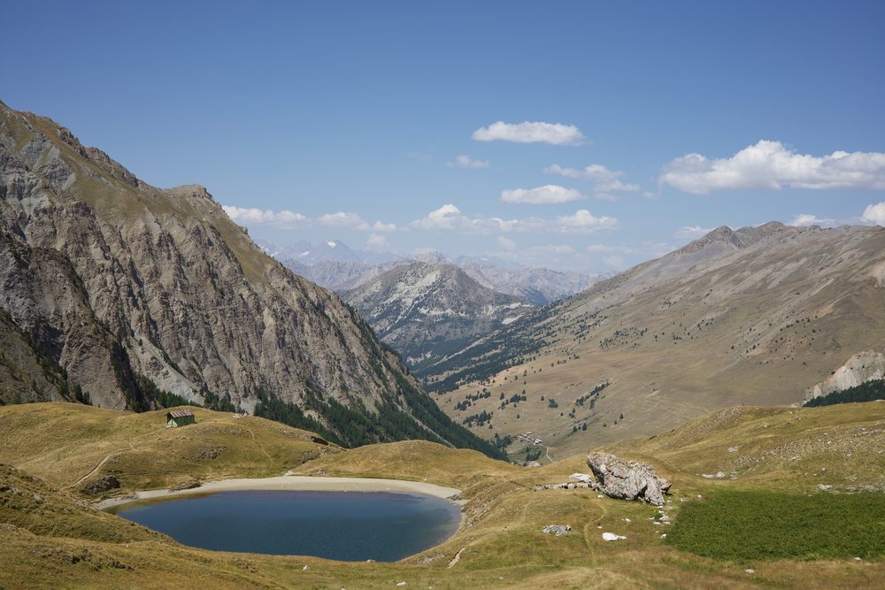 A mountain lake below a rocky slope, with a long valley beyond.